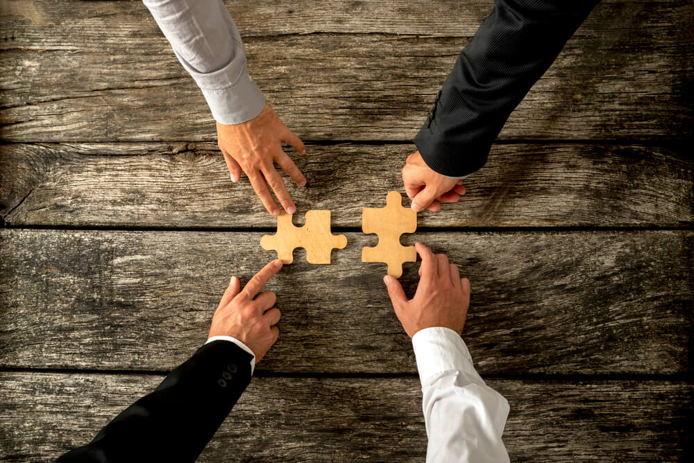four successful business men joining two puzzle pieces each bein